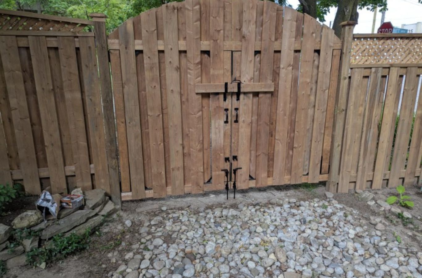 Fence installer measuring post spacing and checking level on uneven residential ground