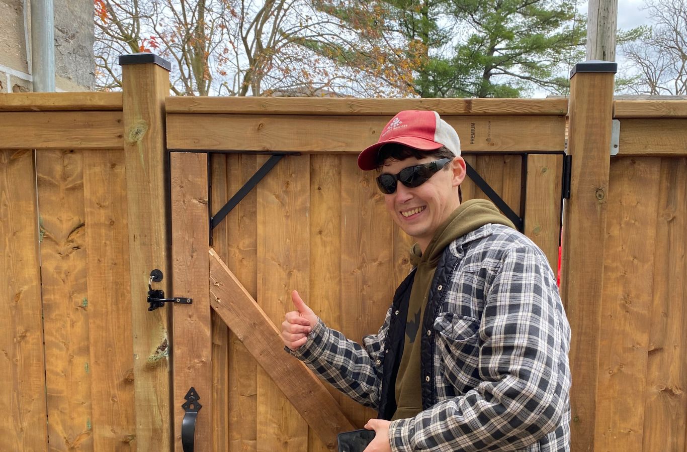 Fence installer measuring post depth and alignment on uneven residential lot