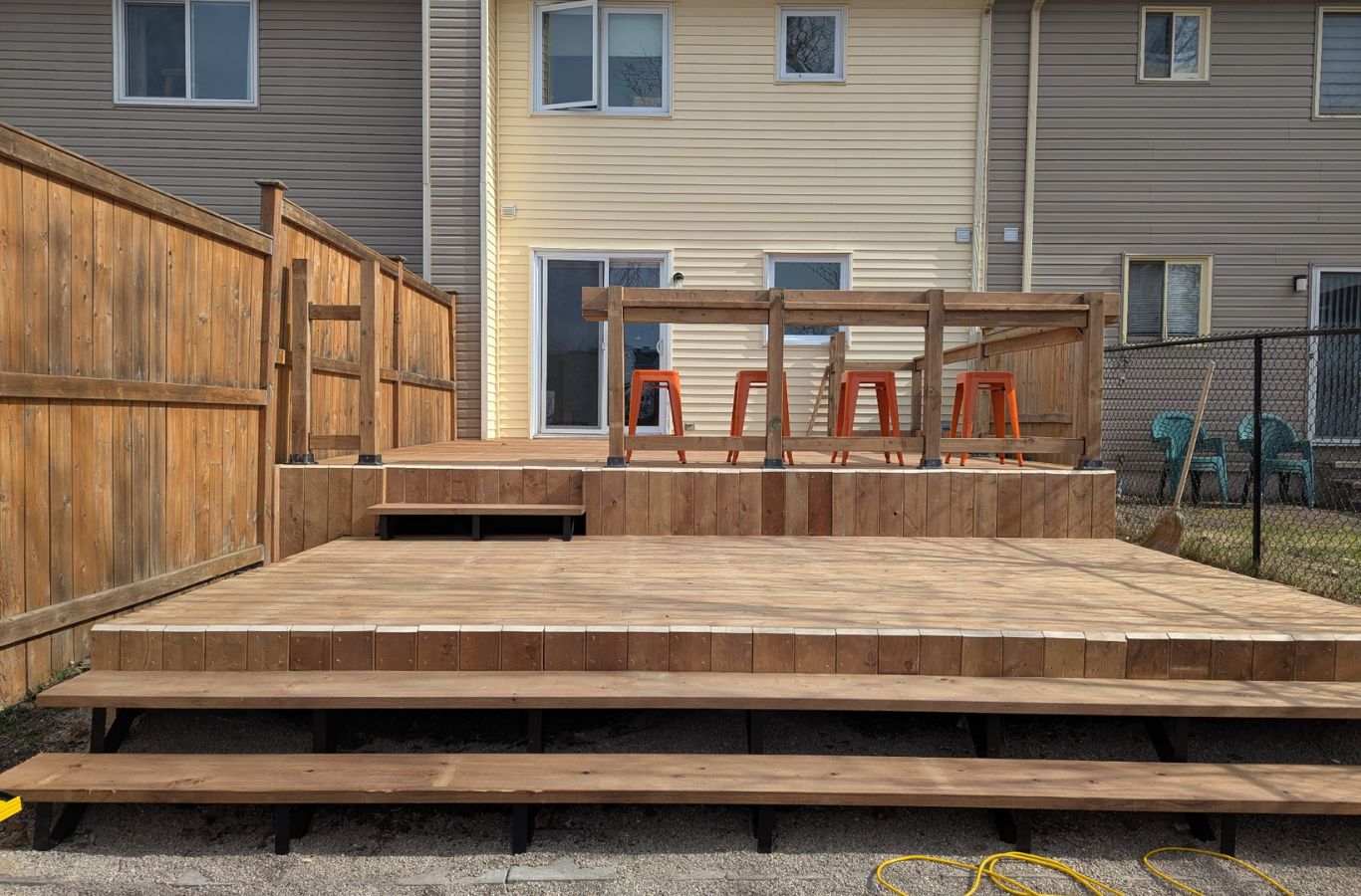 New backyard deck installation behind an Acton home with stairs and railing completed