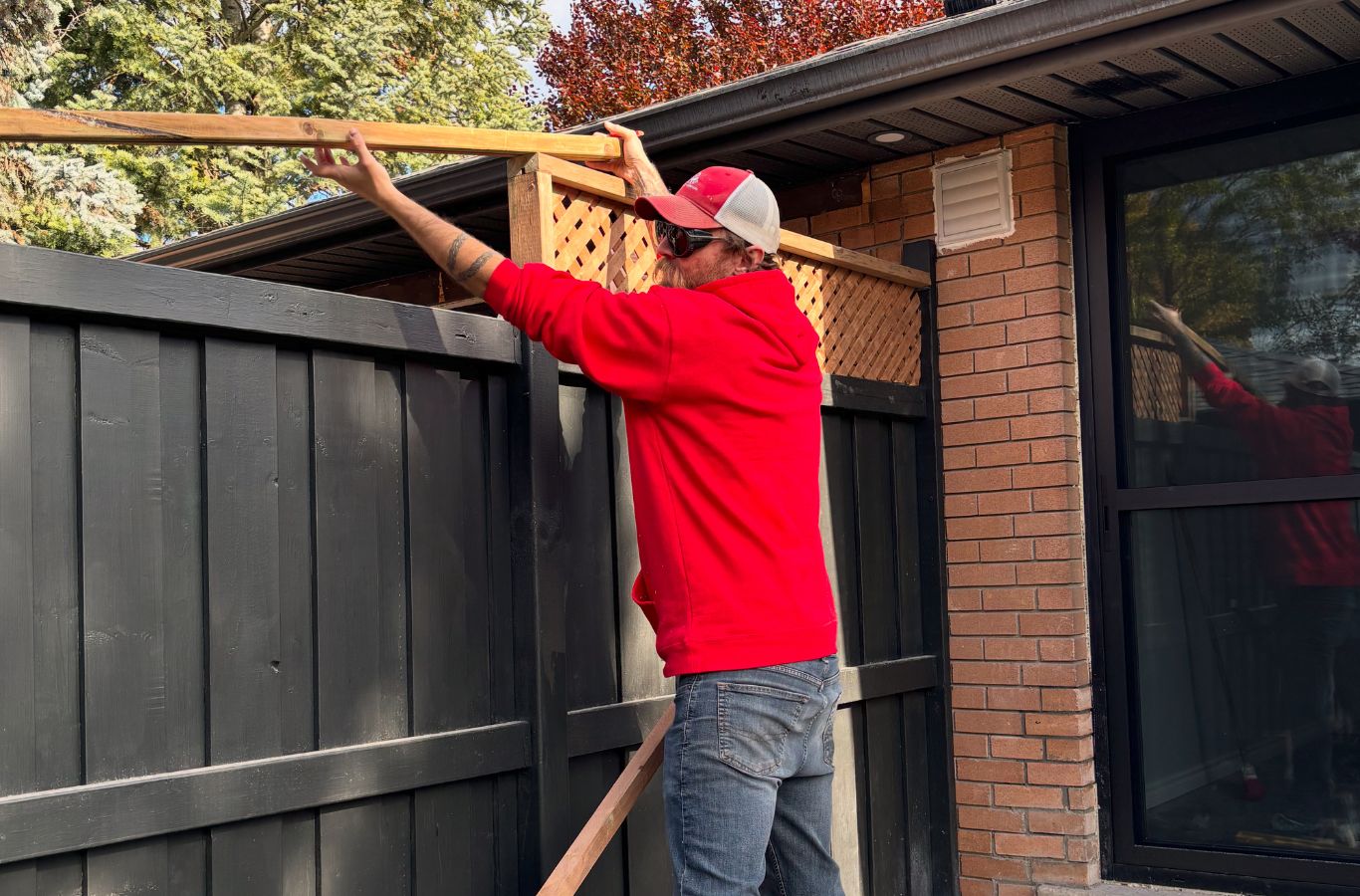 Fence installers setting posts along landscaped backyard edge at Elora home
