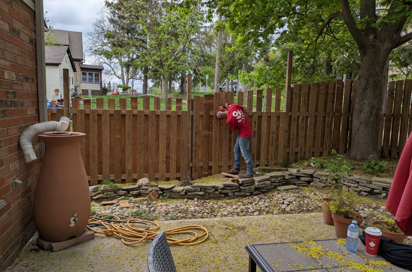 Fence crew installing privacy panels beside sloped backyard at Fergus home